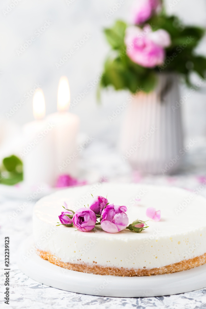 Beautiful white cake decorated pink roses and candles on a white table. Romantic evening Beautiful white cake decorated pink roses and candles on a white table. Romantic evening