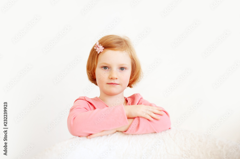 Red-haired girl in a pink T-shirt and bow in her hair on the white background Red-haired girl in a pink T-shirt and bow in her hair on the white background