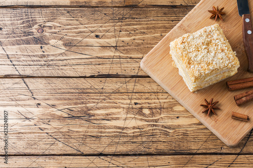Layered cake with cream Napoleon millefeuille vanilla slice with cinnamon and anise on wooden background.