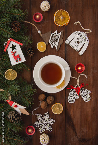 The winter holidays. Christmas tree toys on a brown wooden table. Happy New Year. Hot cup of tea. Top view