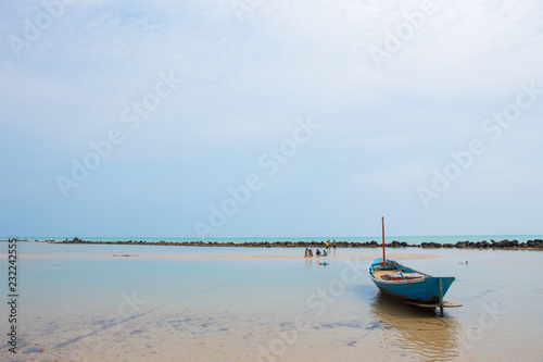 Fishing boat and kids are playing on the beach