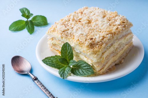 Layer cake with cream Napoleon millefeuille vanilla slice with mint on a colored blue background. photo