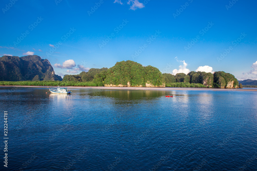 Fototapeta premium Sea background, vivid blue wallpaper, natural scenery (mountains, fishing boats), a common habitat between people and nature.