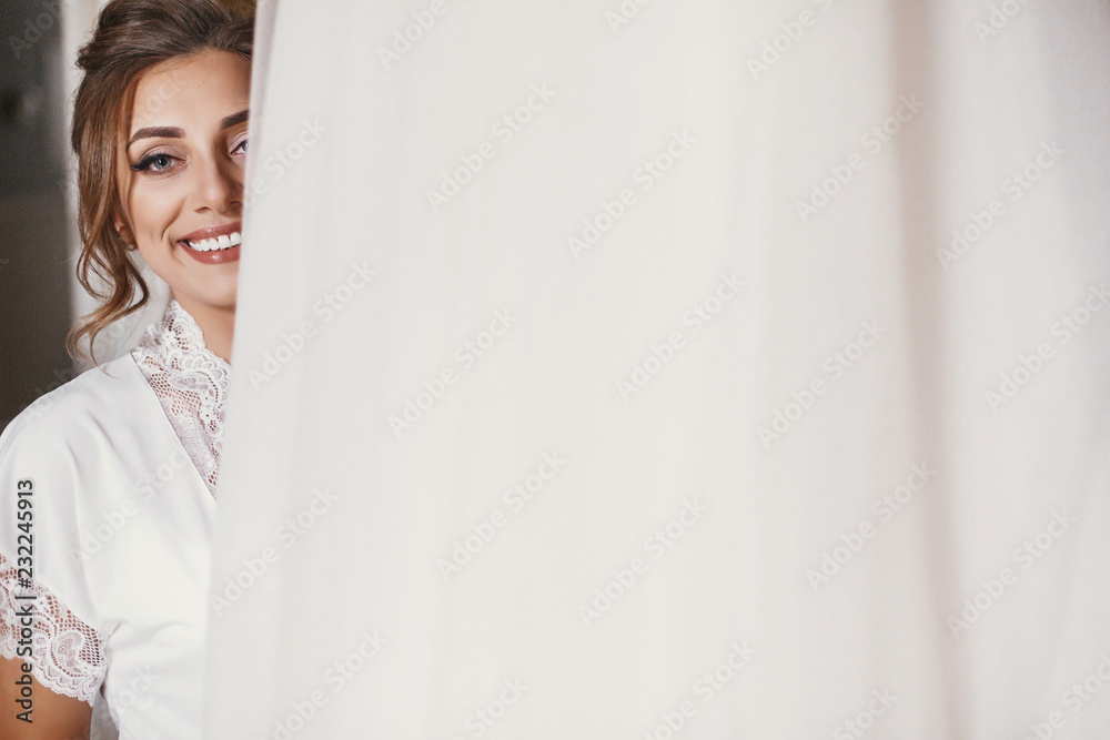Gorgeous bride in silk robe holding stylish wedding dress in room in the morning. Happy sexy Bride and her beautiful wedding gown. Woman smiling and getting ready. Space for text. Gorgeous bride in silk robe holding stylish wedding dress in room in the morning. Happy sexy Bride and her beautiful wedding gown. Woman smiling and getting ready. Space for text.