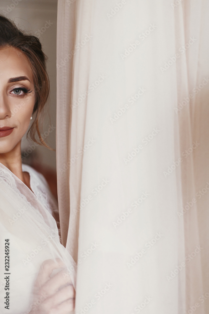 Gorgeous bride in silk robe holding stylish wedding dress in room in the morning. Happy sexy Bride and her beautiful wedding gown. Woman getting ready. Space for text Gorgeous bride in silk robe holding stylish wedding dress in room in the morning. Happy sexy Bride and her beautiful wedding gown. Woman getting ready. Space for text