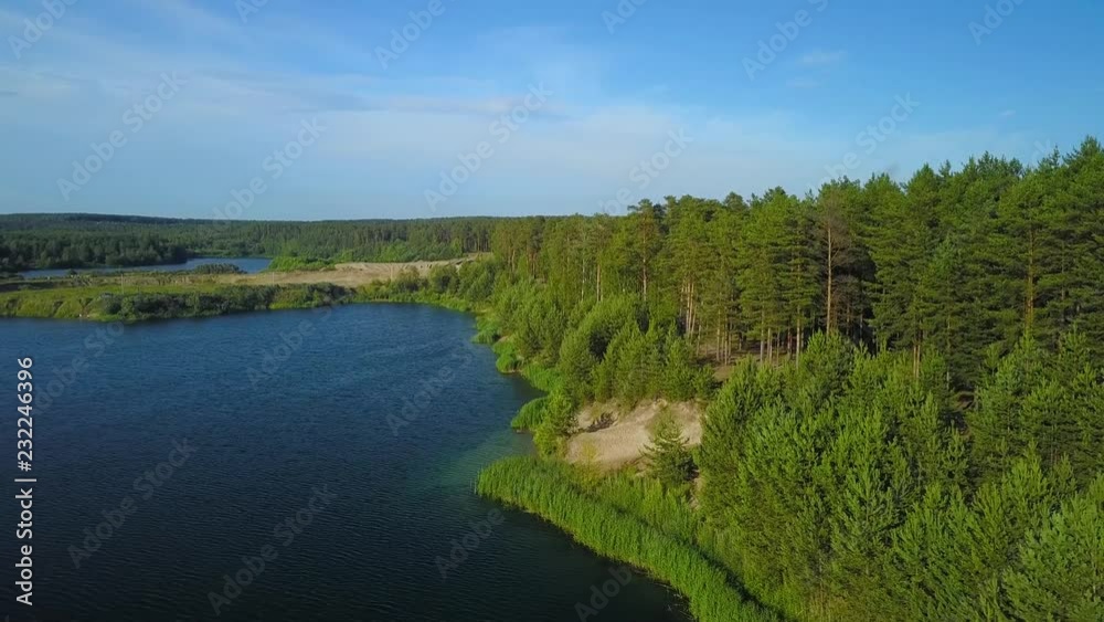 Beautiful blue clear lake on shore with pine trees, aerial shot Beautiful blue clear lake on shore with pine trees, aerial shot