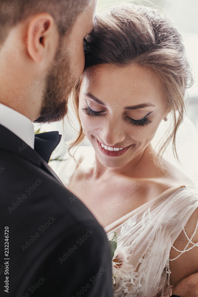 Gorgeous bride and stylish groom gently hugging and embracing at window light. Sensual wedding couple kissing in light. Romantic moments of newlyweds. Wedding photo Gorgeous bride and stylish groom gently hugging and embracing at window light. Sensual wedding couple kissing in light. Romantic moments of newlyweds. Wedding photo