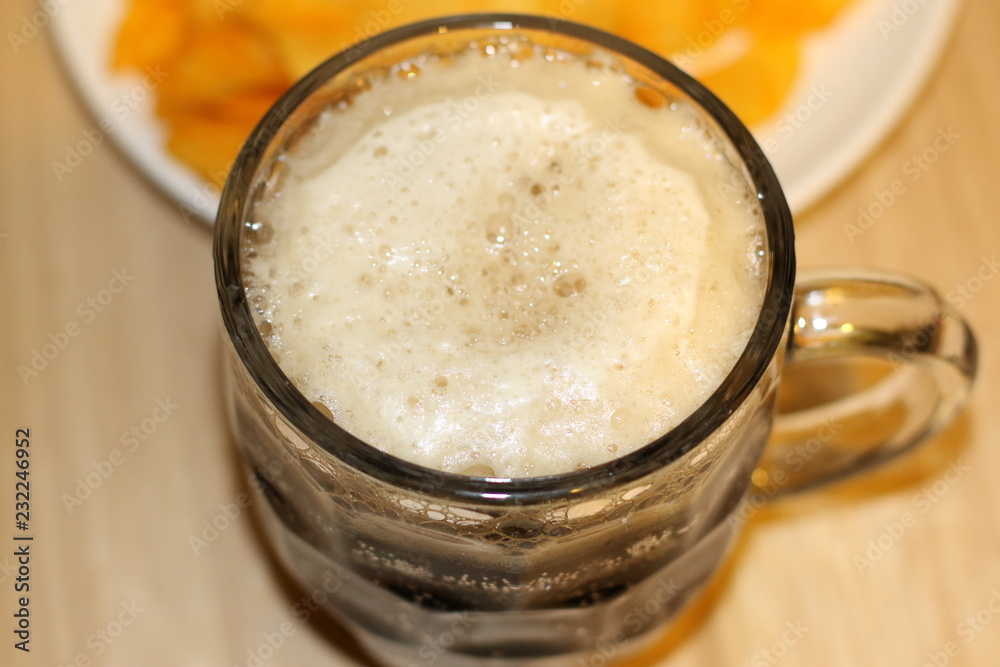 Foamy black beer and crispy chips on white plate Foamy black beer and crispy chips on white plate
