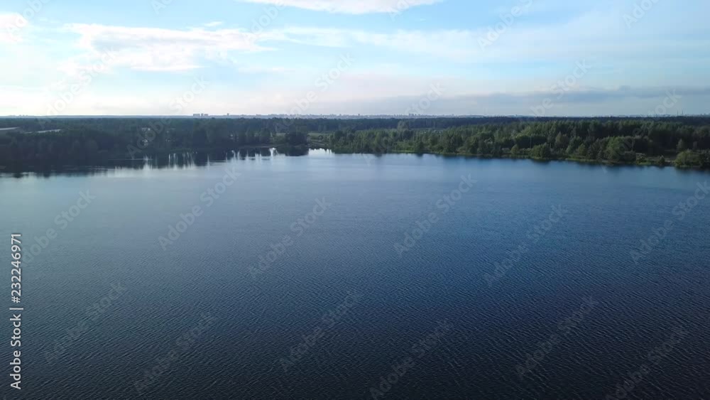 Flying over water surface of forest blue lake Flying over water surface of forest blue lake