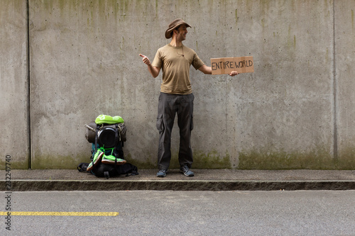 Obraz na plátne A single white adult man with a packed backpack standing on the roadside in fron
