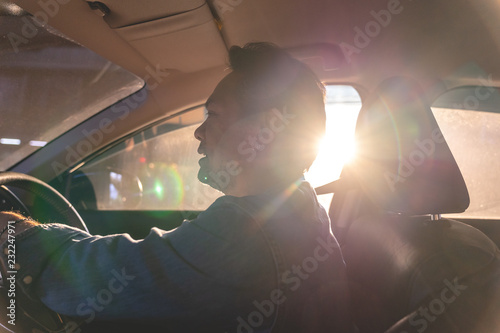 Sticker happy Asian man driving a car with sun ray in background