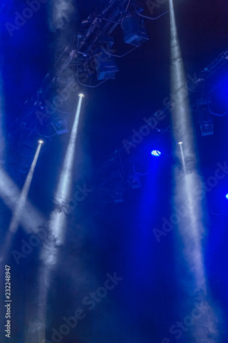 Stage lights. Several projectors in the dark. Multi-colored light beams from the stage spotlights on the stage in the smoke at the time of the entertainment show. Night club. Lights show. Lazer show