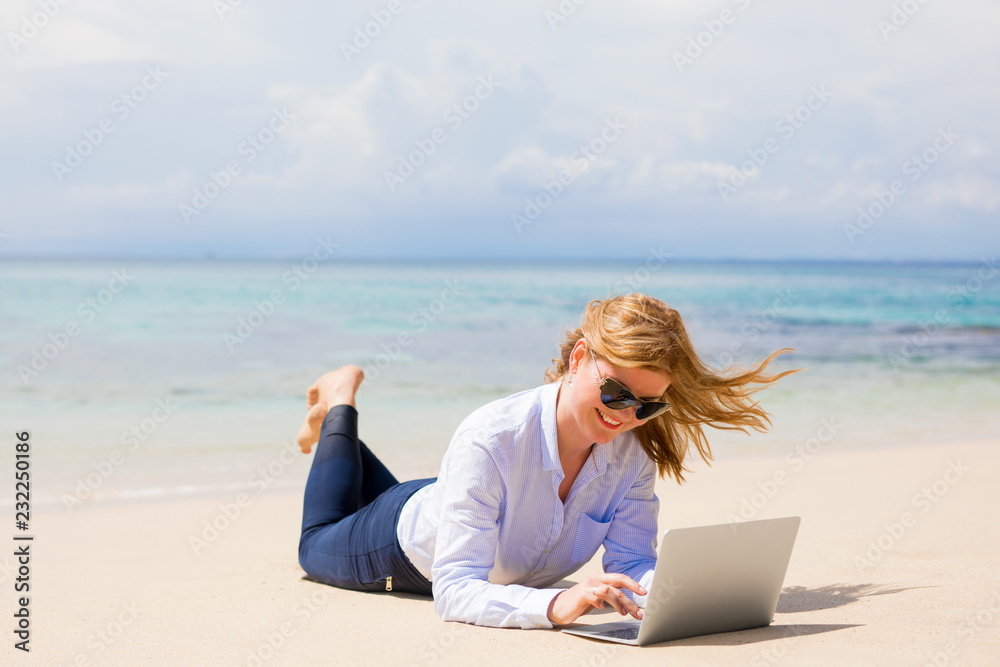 Happy business woman with laptop on the beach