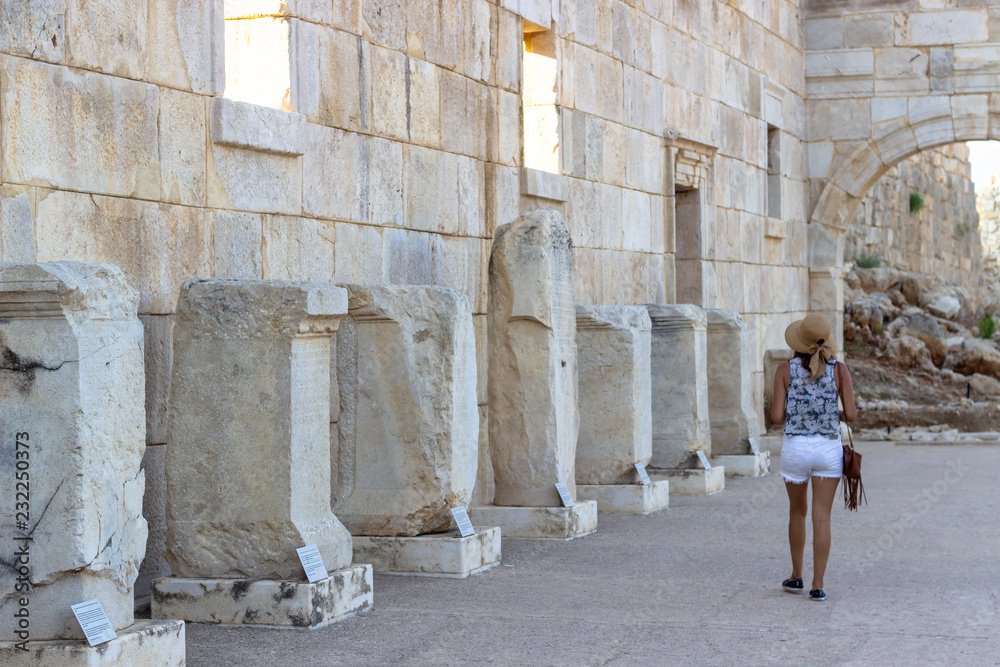 Woman promenades in the ancient historical structures and observe old columns information