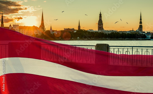 Conceptual collage image symbolizing 100 years of Latvian State Independence. Flag of Latvian State and background of mediaval historical center of Riga -capital of Latvia, EC photo