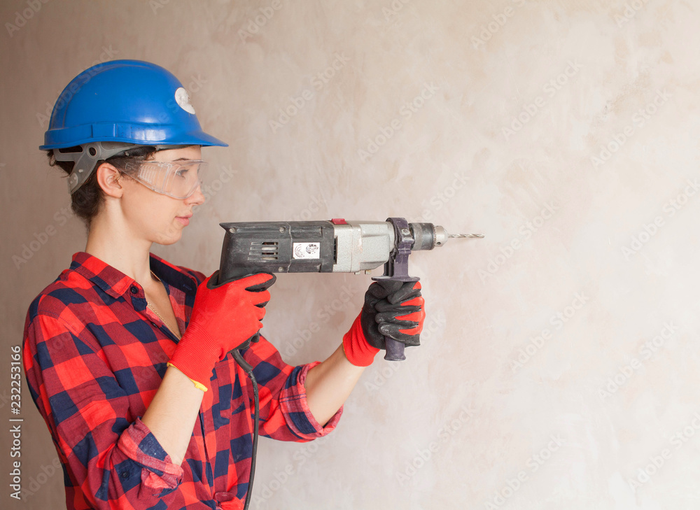 Woman builder worker with drill standing against white background. Construction. Building tools