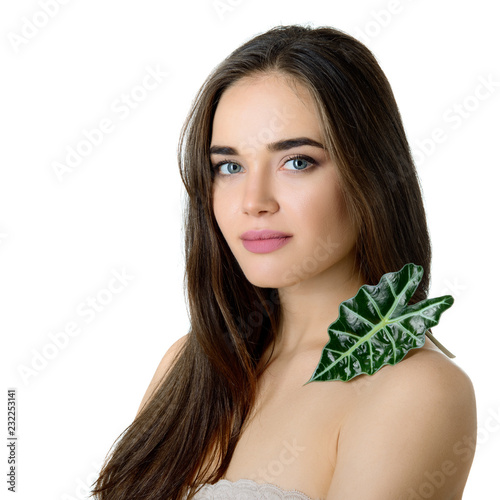 Gorgeous girl with cleann skin and perfect hair holding green fresh leaf on her shoulder, studio shot isolated on white background. Beautiful young woman's portrait. Care of mother-nature.  photo