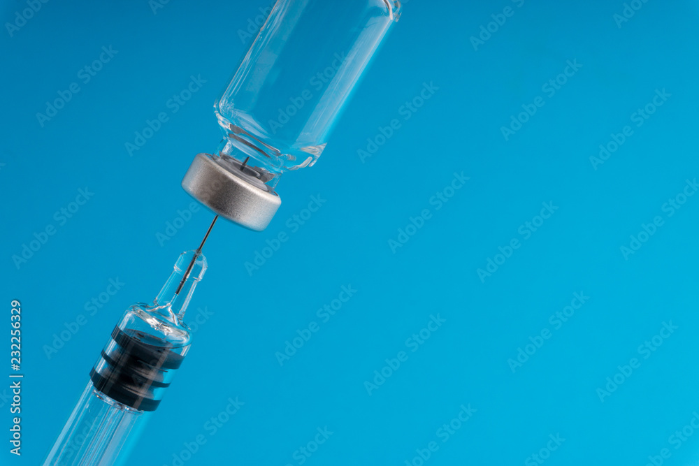 Medical syringe and vial on blue background with selective focus and crop fragment Medical syringe and vial on blue background with selective focus and crop fragment