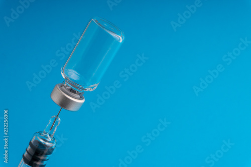Medical syringe and vial on blue background with selective focus and crop fragment