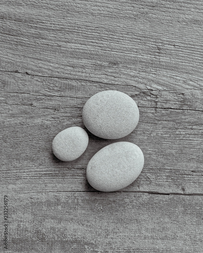 Canvas Print Smooth grey pebble on old wooden background with copy space