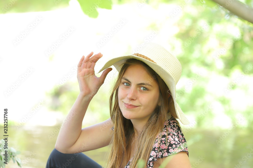 Young and pretty woman with a hat with a nature background