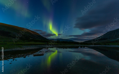 aurora borealis in the night sky cut the mountains, reflected in the water © Igor Dmitriev