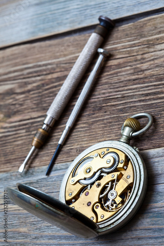 reverse side of the vintage pocket watch and a screwdriver