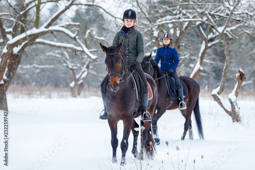 Two young women riding horses in winter park