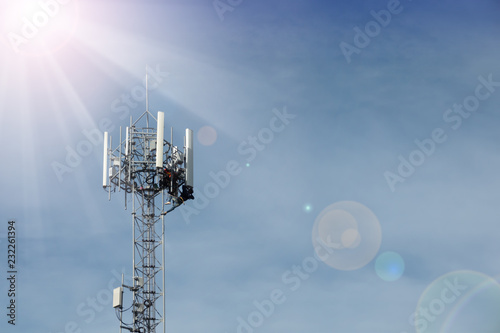 Professional services for smart phone wireless network..Unidentified technicians working on 4G antenna tower for routine maintenance with safety equipment with sunray and bokeh.
