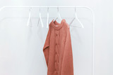 One orange pastel knit warm sweater on hanger and many empty hangers.