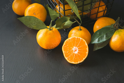 Fresh mandarins with leaves in modern bowl on black. Healthy eating concept. Copy space.