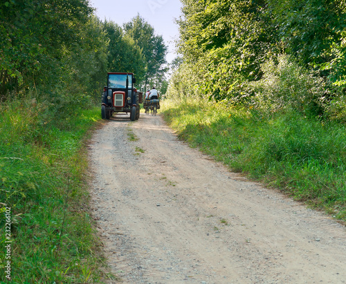 Tractor in rural area. A tractor ride on a gravel road towards cyclists  tourists.