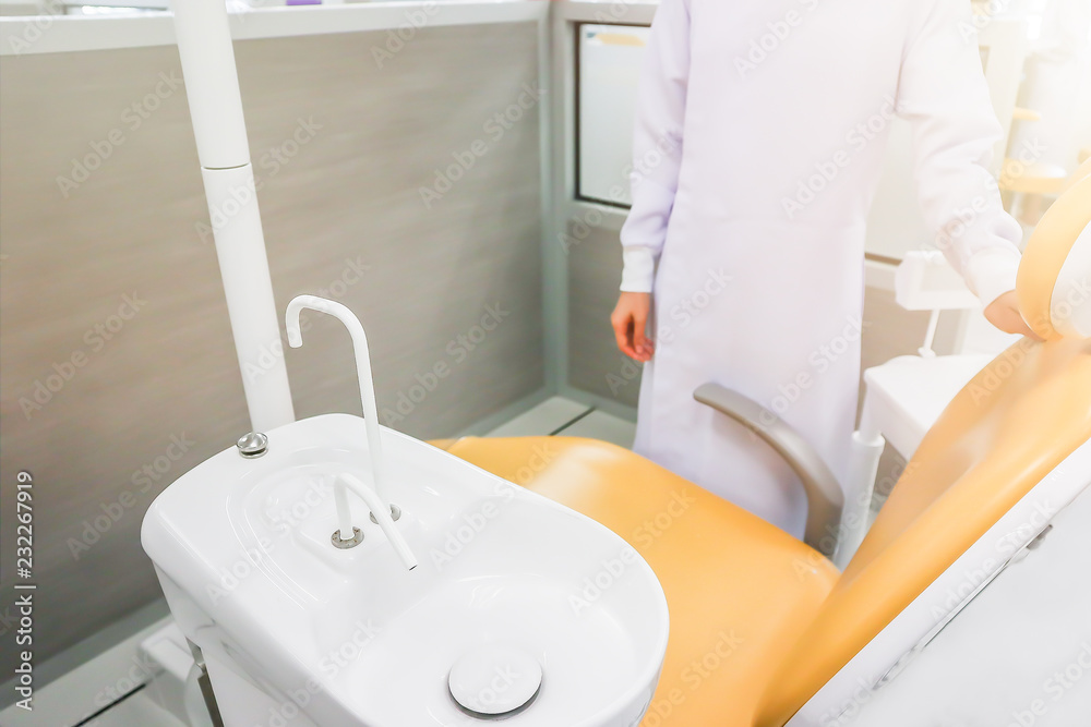 dentist standing beside the dental chair with the sink Stock Photo