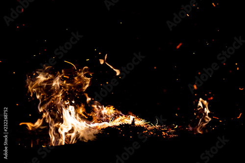 Burning woods with firesparks, flame and smoke. Strange weird odd elemental fiery figures on black background. Coal and ash. Abstract shapes at night. Bonfire outdoor on nature. Strenght of element. © benevolente