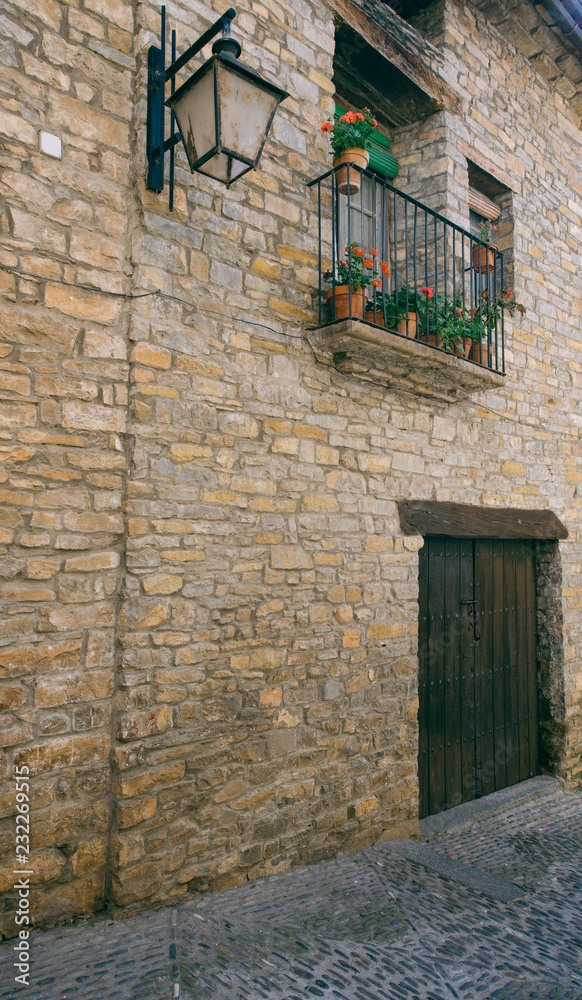 Streets with rustic houses built with stones and decorated with flowers. Mountain village.