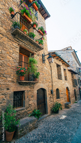 Streets with rustic houses built with stones and decorated with flowers. Mountain village. © Freestocker