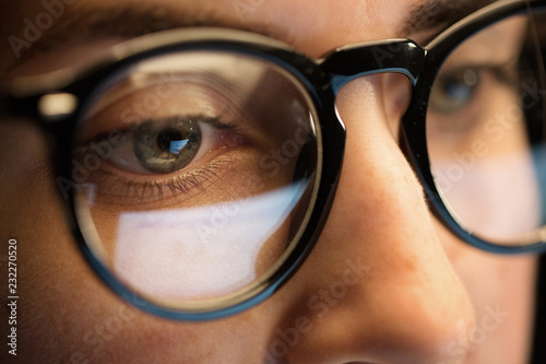 vision, business and education concept - close up of woman eyes in glasses looking at computer screen