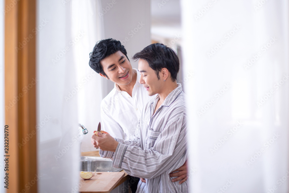 Male gay couple preparing a meal together in the kitchen Male gay couple preparing a meal together in the kitchen