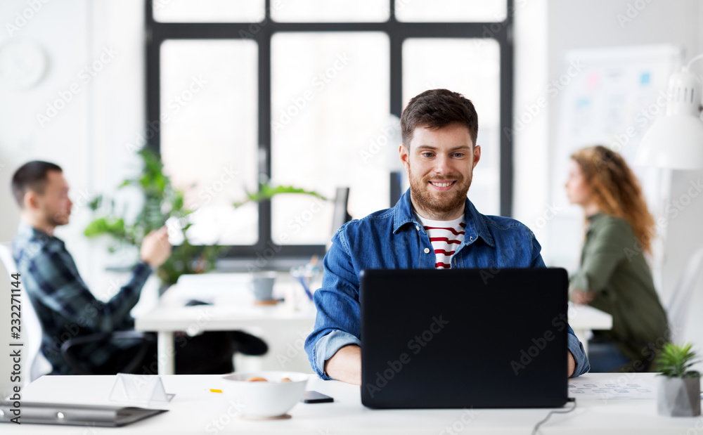 business, technology and people concept - happy smiling creative man with laptop computer working at office business, technology and people concept - happy smiling creative man with laptop computer working at office