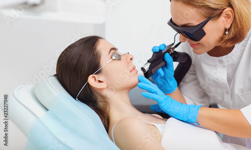 Laser hair removal on the face of a young woman in a cosmetology