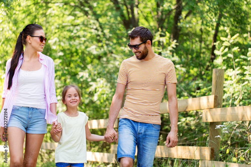 family, leisure and people concept - happy mother, father and little daughter walking in summer park