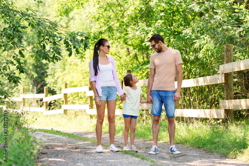family, leisure and people concept - happy mother, father and little daughter walking in summer park