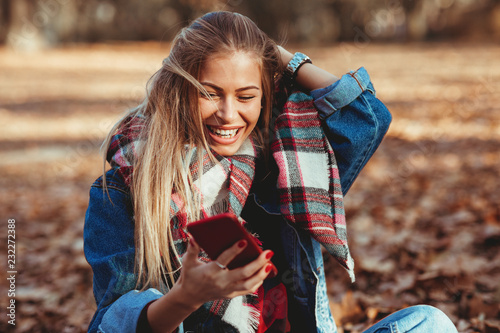Young woman in the park using smartphone  and laughing