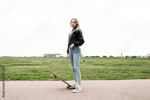 Teenage girl standing with skate board with attitude 
