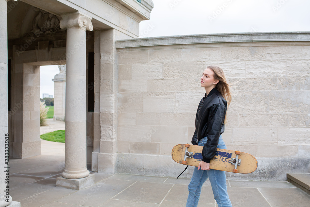 teenage girl posing while holding her skate board