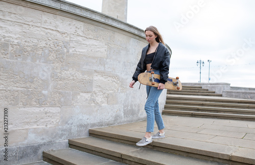 Girl texting while walking with a skate board