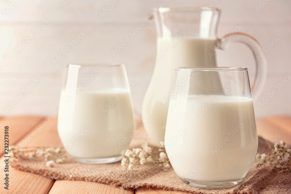 Composition with glasses and jug of tasty milk on wooden table Composition with glasses and jug of tasty milk on wooden table