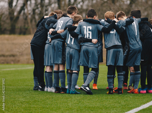 Boys Soccer Team Doing Motivational Pre Game Chant. Young Footballers Standing Together United and Listening Coach Motivational Speech. Kids Sports Team Wearing Grey Soccer Kit and Football Cleats