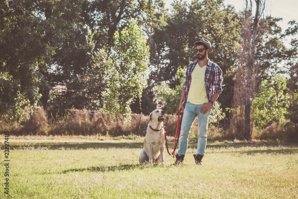 Young man posing with his canadian labrador dog in an urban park Young man posing with his canadian labrador dog in an urban park