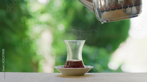 Slow motion shot of preparing Turkish tea in a garden with green background surrounded with trees. 